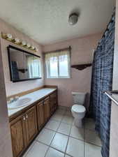 Full bath with vanity, a textured ceiling, and tile patterned floors
