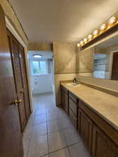 Bathroom featuring vanity, a textured ceiling, tile patterned flooring, tile walls, and a closet