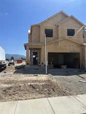 View of front of property featuring a mountain view, dirt driveway, and an attached garage