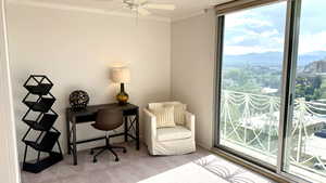 Carpeted office space featuring crown molding, a mountain view, a ceiling fan, and a view of city