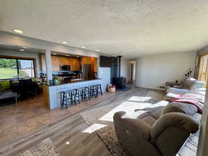 Living area with a textured ceiling, a wood stove, recessed lighting, and wood finished floors