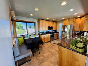 Kitchen featuring cozy seating area, appliances with stainless steel finishes, recessed lighting, dark stone countertops