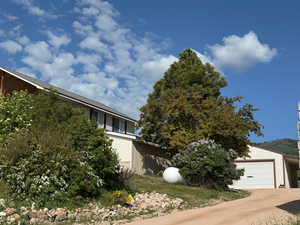 View of side of home featuring an attached garage and gravel driveway to detached garage