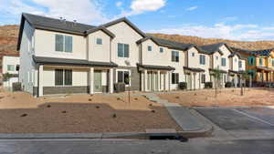 Townhome / multi-family property with stucco siding, brick siding, a residential view, and uncovered parking