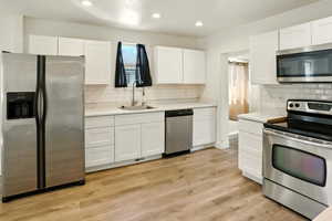 Kitchen with appliances with stainless steel finishes, white cabinets, light countertops, backsplash, and recessed lighting