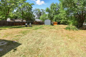Fenced backyard featuring a storage unit