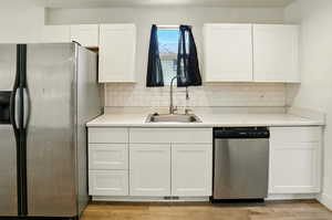 Kitchen with appliances with stainless steel finishes, white cabinets, tasteful backsplash, and light countertops