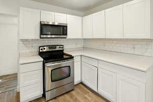 Kitchen featuring appliances with stainless steel finishes, white cabinets, and light wood-type flooring