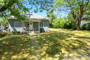 Front view of property with a porch, a lawn, and roof with shingles
