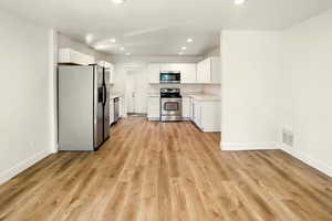 Living Room with view into Kitchen and appliances with stainless steel finishes, light countertops, recessed lighting, white cabinetry, and decorative backsplash