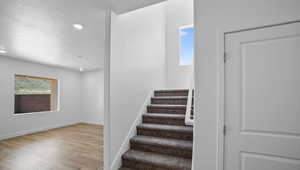 Staircase with wood finished floors, recessed lighting, and a textured ceiling