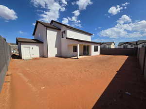 Rear view of house featuring stucco siding, a fenced backyard, and a patio area