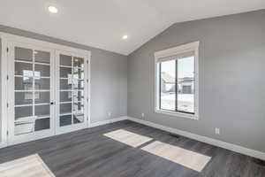 Spare room with french doors, dark wood-type flooring, vaulted ceiling, and recessed lighting