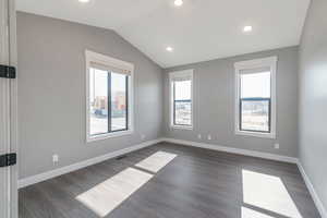 Empty room featuring lofted ceiling, dark wood finished floors, and recessed lighting