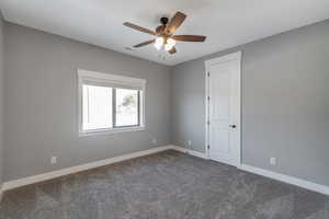 Spare room featuring dark colored carpet and ceiling fan