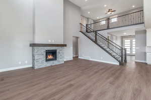 Unfurnished living room featuring a high ceiling, a ceiling fan, stairs, recessed lighting, and wood finished floors