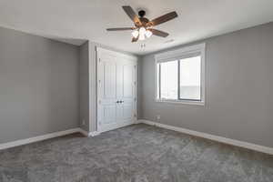 Unfurnished bedroom with carpet, a closet, and ceiling fan