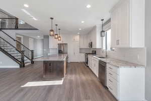 Kitchen featuring stainless steel appliances, wood finished floors, recessed lighting, tasteful backsplash, and a kitchen island