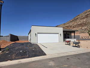 View of front of house with an attached garage, concrete driveway, and stucco siding