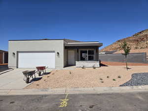 View of front of home with concrete driveway, an attached garage, stucco siding, and a mountain view
