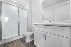 Bathroom with vanity, wood finished floors, a shower stall, and recessed lighting