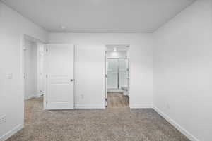 Unfurnished bedroom with carpet flooring and connected bathroom