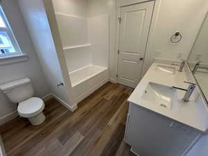 Bathroom featuring double vanity, wood finished floors, and shower / bathtub combination