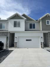 View of property with stone siding, board and batten siding, an attached garage, and driveway
