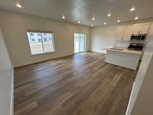 Kitchen featuring appliances with stainless steel finishes, open floor plan, recessed lighting, dark wood finished floors, and white cabinets