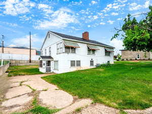 Back of house featuring a chimney and roof with shingles