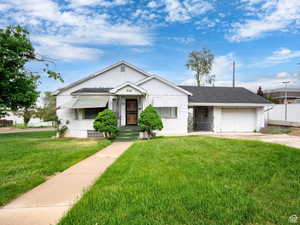 View of front of house featuring a front yard, a garage, driveway, and a shingled roof