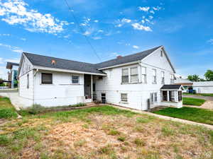 Back of house featuring a shingled roof and a lawn