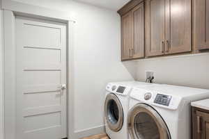 Washroom featuring cabinet space, washer and clothes dryer located by double garage