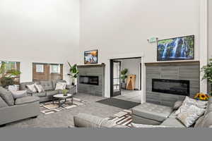 Living area with a fireplace, carpet flooring, and a high ceiling