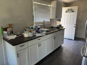 Kitchen featuring dark countertops, dark wood-style flooring, and white cabinetry