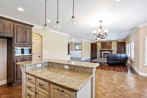 Kitchen with stainless steel microwave, built in features, light tile patterned floors, arched walkways, and light stone counters