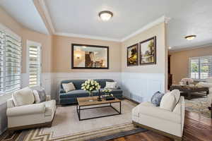 (Virtual Staging) Living room featuring ornamental molding, wood finished floors, and a wainscoted wall