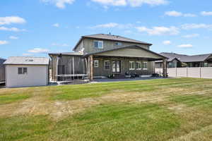 Back of house with a patio area, a trampoline, board and batten siding, an outdoor structure, and entry steps
