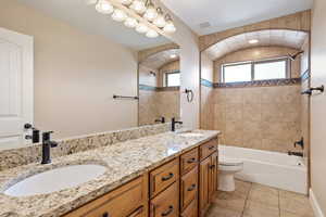 Bathroom featuring double vanity, bathing tub / shower combination, and tile patterned floors