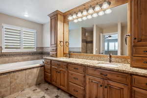 Primary suite bathroom featuring double vanity, a garden tub, tiled shower, and tile patterned flooring