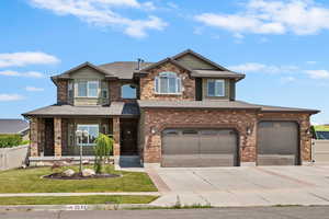 View of front facade featuring concrete driveway, an attached garage, a shingled roof, brick siding, and stone siding