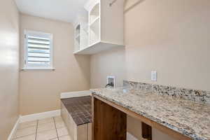 Laundry room with washer hookup, light tile patterned flooring, and a desk