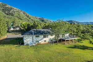 Back of house with a yard and a deck with mountain view