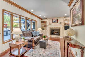 Large windows fill this room with natural light, which features recessed lighting, hardwood floors, a fireplace, built-in bookcases and custom wood molding