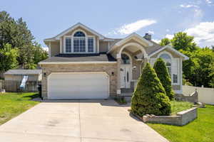 Traditional-style home with driveway, a garage, a chimney, stucco siding, and brick siding