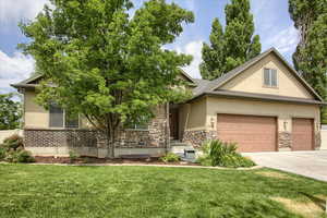 View of front of house featuring stucco siding, a front lawn, a garage, and driveway