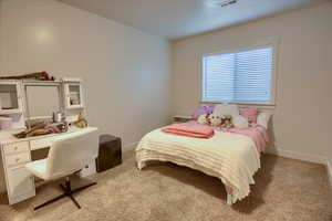 Bedroom with light carpet and an office area