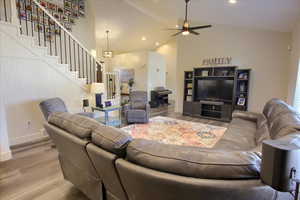 Living area with stairway, wood finished floors, ceiling fan, recessed lighting, and high vaulted ceiling