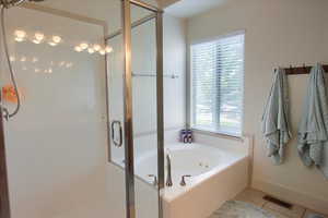 Bathroom featuring a stall shower, tile patterned flooring, and a whirlpool tub