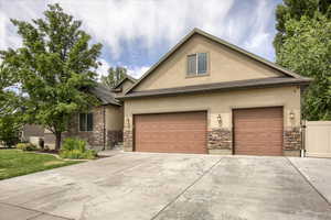 View of front of house featuring stone siding, stucco siding, and concrete driveway